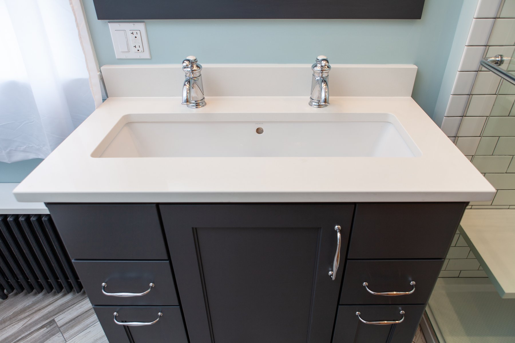 small bathroom remodel with black cabinets and chrome hardware with a double-sink and painted floor heater