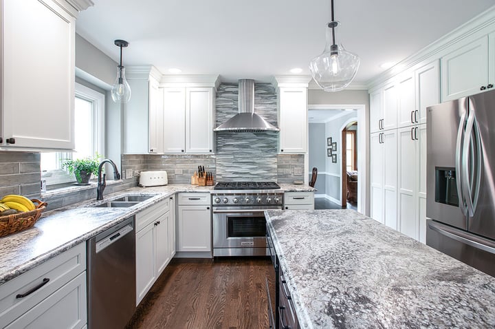Remodeled kitchen in Libertyville, Illinois with hardwood floor, white cabinets, modern drop lighting, stainless steel appliances and a fresh new backsplash.