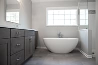 Beautiful modern bathroom remodel in Lake Zurich with natural gray cabinets, chrome finishes and white tub.