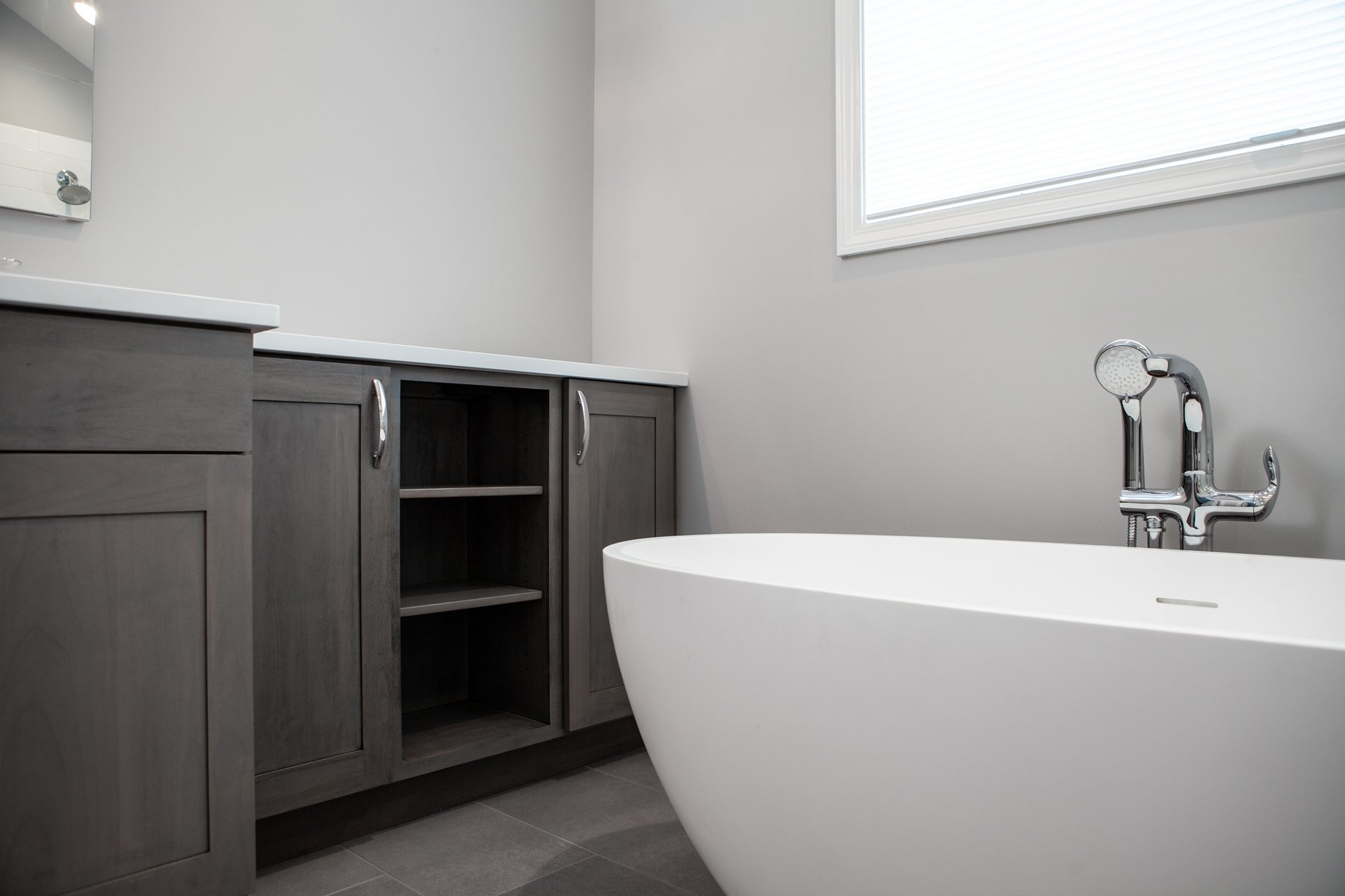 Beautiful modern bathroom remodel in Lake Zurich with natural gray cabinets, chrome finishes and white tub.