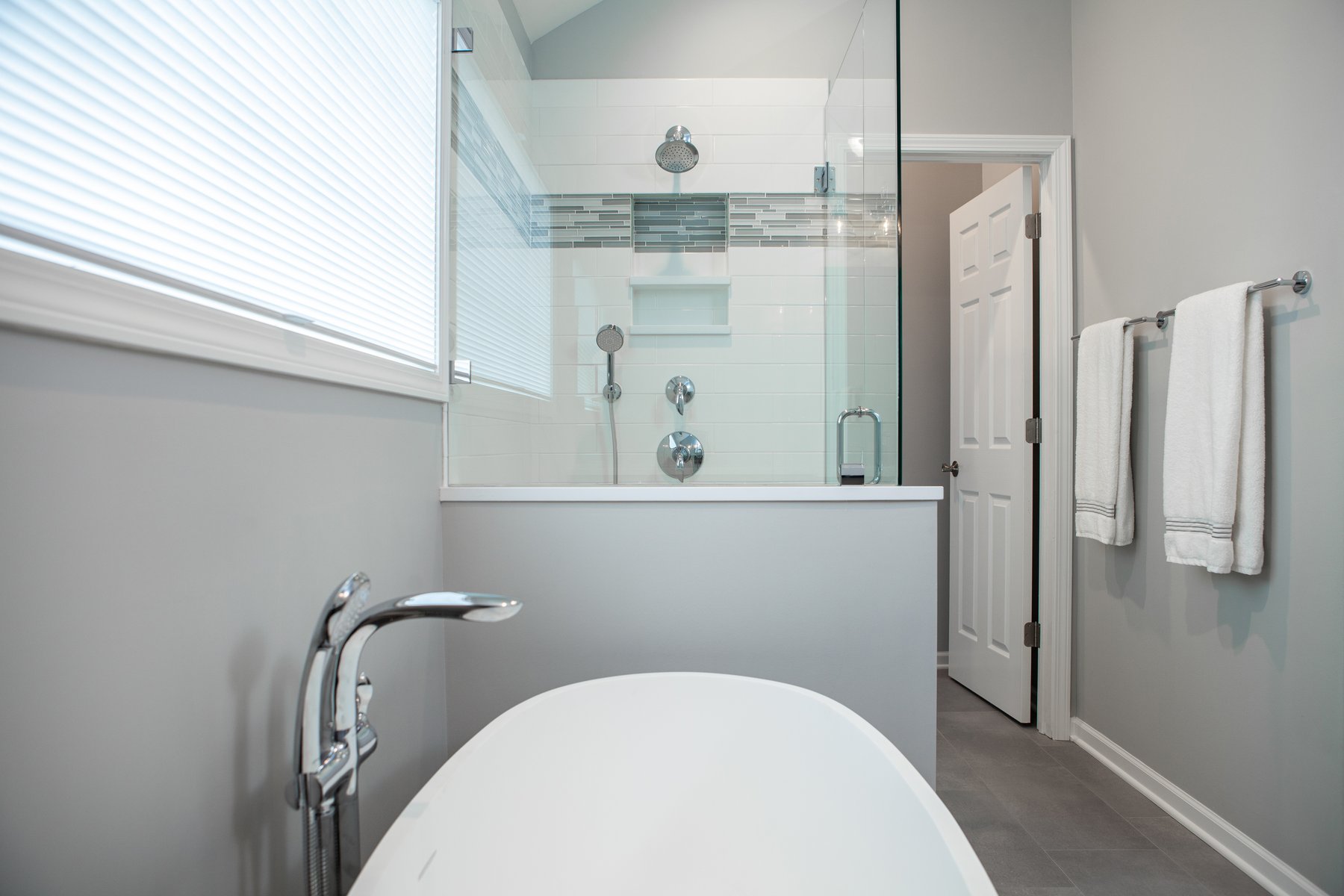 Beautiful modern bathroom remodel in Lake Zurich with white tub and glass shower surround..