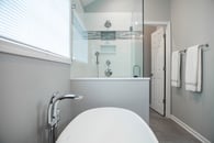Beautiful modern bathroom remodel in Lake Zurich with white tub and glass shower surround..