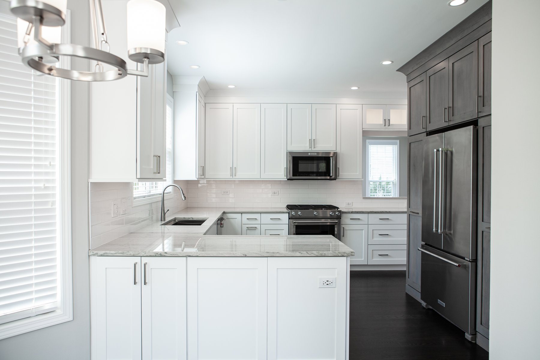 Beautiful modern kitchen remodel in Lake Zurich with natural wood floors, white cabinets and wooden accent cabinetry around the refrigerator.