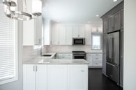 Beautiful modern kitchen remodel in Lake Zurich with natural wood floors, white cabinets and wooden accent cabinetry around the refrigerator.