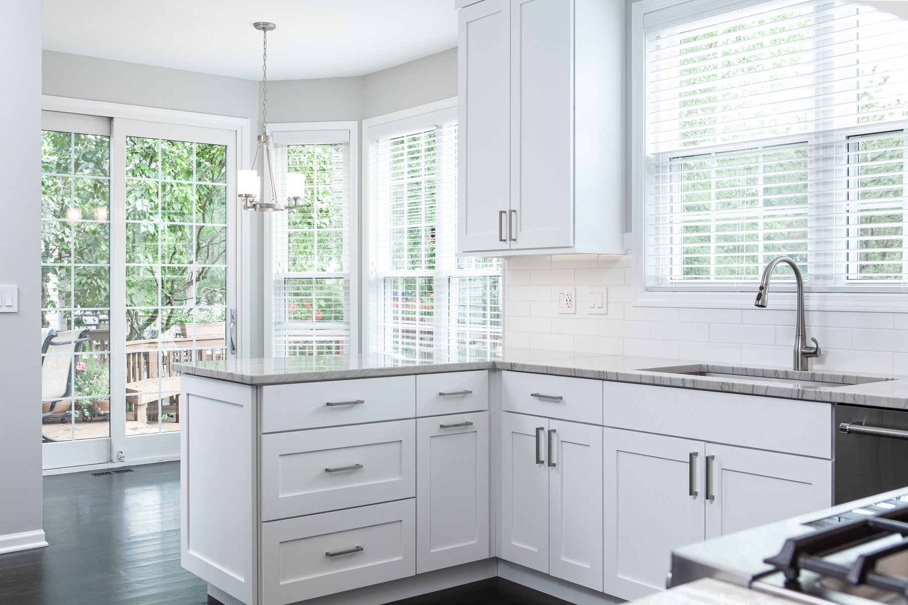 Beautiful modern kitchen remodel in Lake Zurich with natural wood floors, white cabinets and open lighting from surrounding windows.