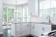 Beautiful modern kitchen remodel in Lake Zurich with natural wood floors, white cabinets and open lighting from surrounding windows.