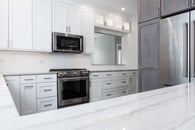 Beautiful modern kitchen remodel in Lake Zurich with natural wood floors, white cabinets and wooden accent cabinetry around the refrigerator.
