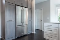 Beautiful modern kitchen remodel in Lake Zurich with natural wood floors, white cabinets and wooden accent cabinetry around the refrigerator.
