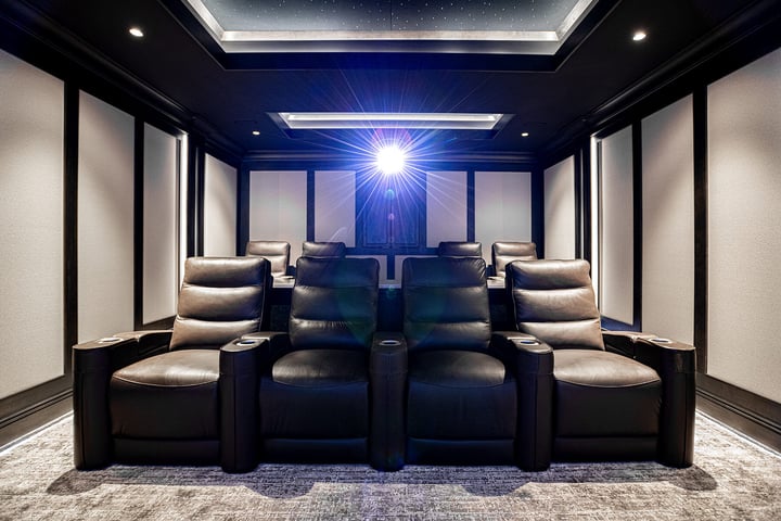 Home theater with two levels of leather theater chairs paneled walls and a projector ceiling has led lights and stars