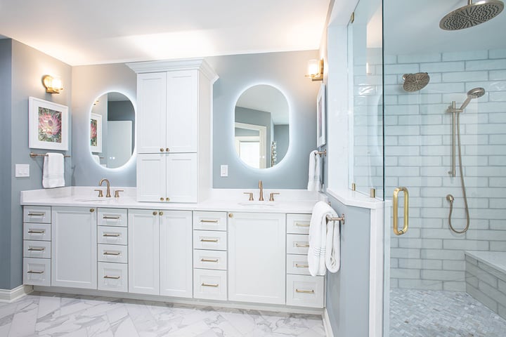 Remodeled bathroom with white cabinetry, gold finishes and gray painted walls with a beautiful subway tile in the glass enclosed shower.