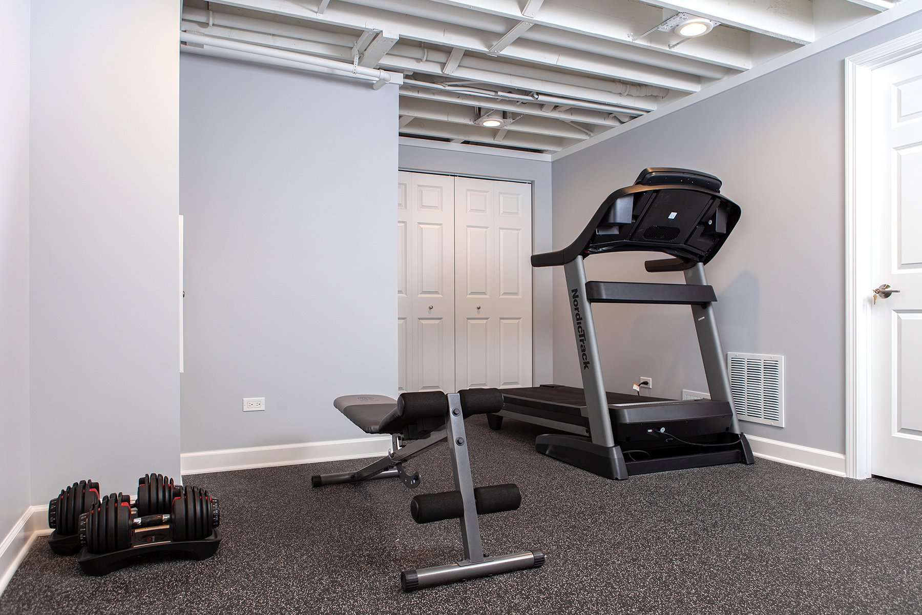 Remodeled basement workout room in Libertyville, Illinois with treadmill, free-weights and padded floors.