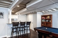 Remodeled basement in Libertyville, Illinois with hardwood floors, pool table, workout room and small kitchen.