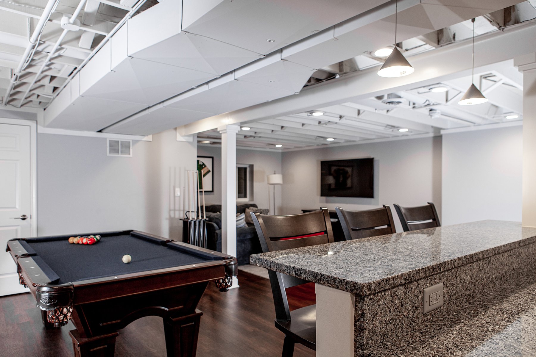 Remodeled basement in Libertyville, Illinois with hardwood floors, pool table, workout room, lounge area and kitchen.