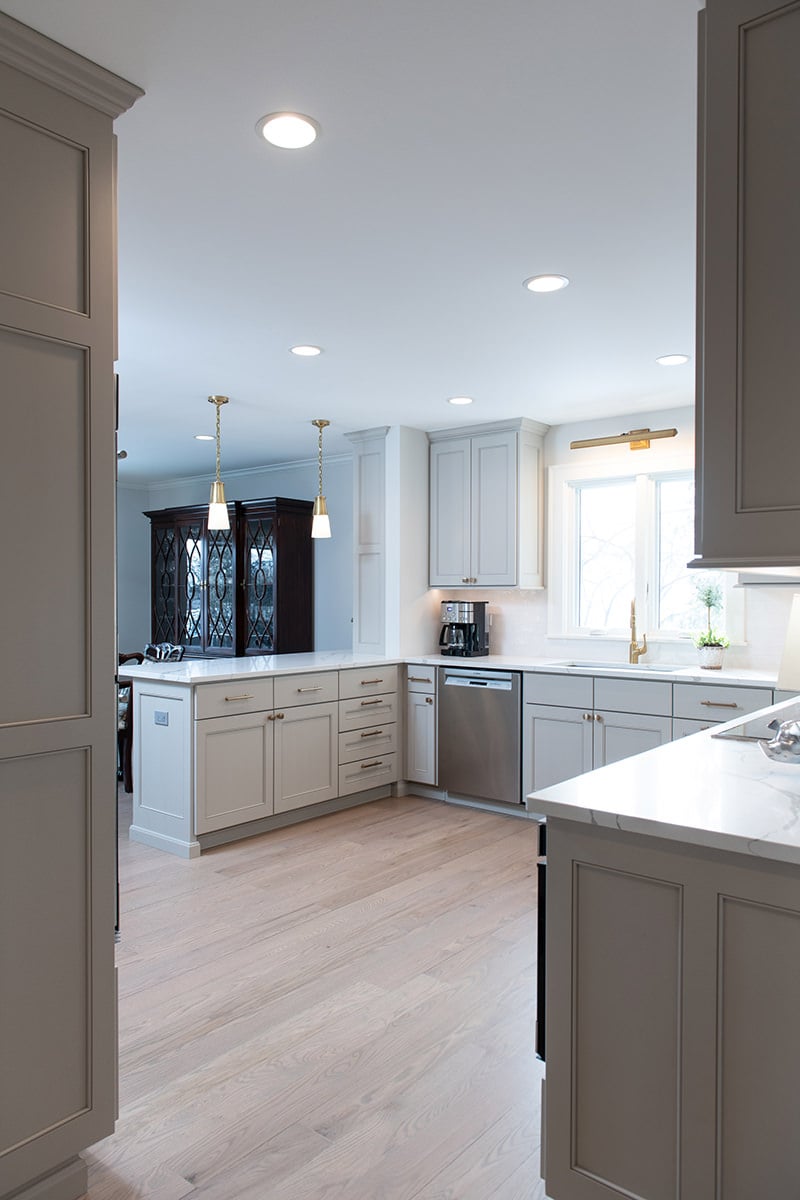 Kitchen renovation with gray painted cabinets, gold hardware, white marble countertops and a backsplash with white subway tile.