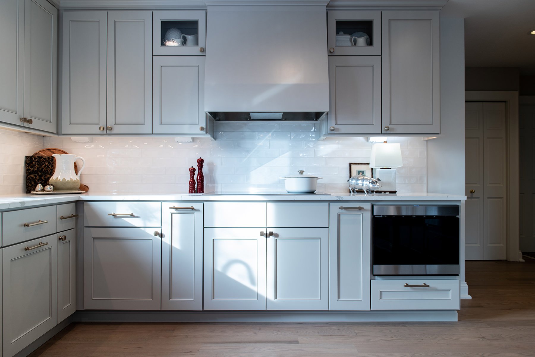 Kitchen renovation with gray painted cabinets, gold hardware, white marble countertops and a backsplash with white subway tile.