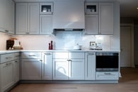 Kitchen renovation with gray painted cabinets, gold hardware, white marble countertops and a backsplash with white subway tile.