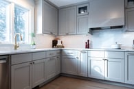 Kitchen renovation with gray painted cabinets, gold hardware, white marble countertops and a backsplash with white subway tile.
