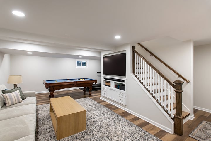 Updated basement in Libertyville with wood flooring, built-in tv cabinet, a pool table, recessed lighting and neutral paint colors throughout.