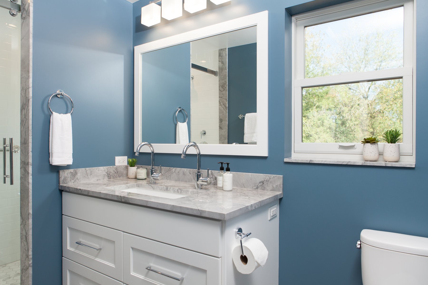 Classic style in this hall bath remodel in Libertyville, Illinois with blue walls, white cabinetry, chrome hardware and gray countertops.
