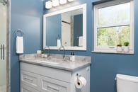 Classic style in this hall bath remodel in Libertyville, Illinois with blue walls, white cabinetry, chrome hardware and gray countertops.