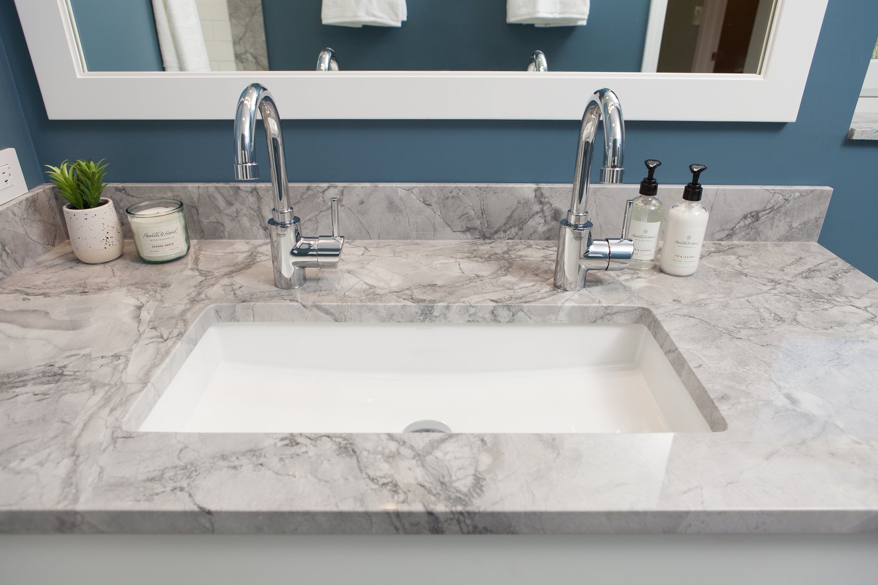 Classic style in this hall bath remodel in Libertyville, Illinois with blue walls, white mirror, chrome hardware and gray countertops including double faucets with a single basin sink.