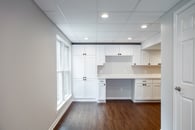 Remodeled basement in Lake Bluff, Illinois with white cabinetry, hardwood flooring, light gray wall paint and lots of windows throughout.