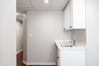 Remodeled basement with custom white cabinetry, hardwood flooring, light gray wall paint and lots of windows throughout.