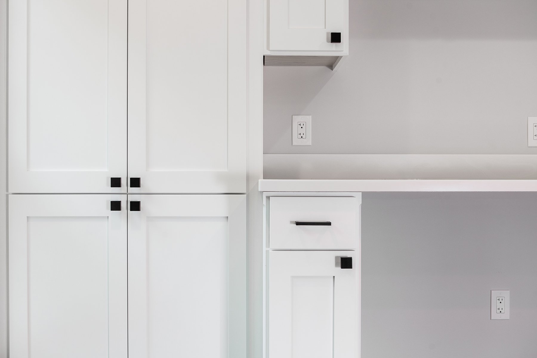 Remodeled basement with custom white cabinetry and light gray wall paint.