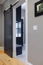 Black barn door paired with light wood flooring and a modern patterned tile give this home a modern look.