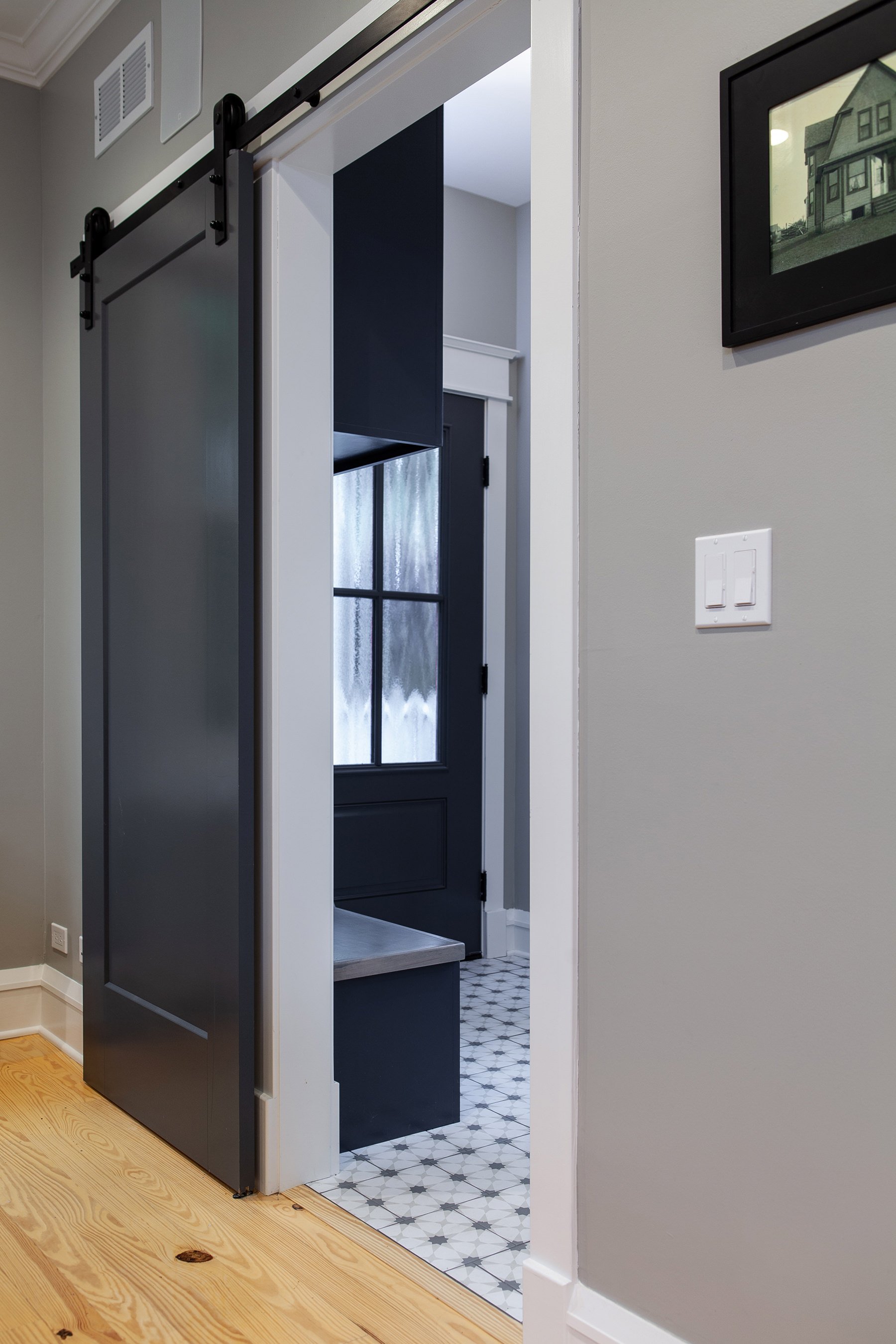 Black barn door paired with light wood flooring and a modern patterned tile give this home a modern look.