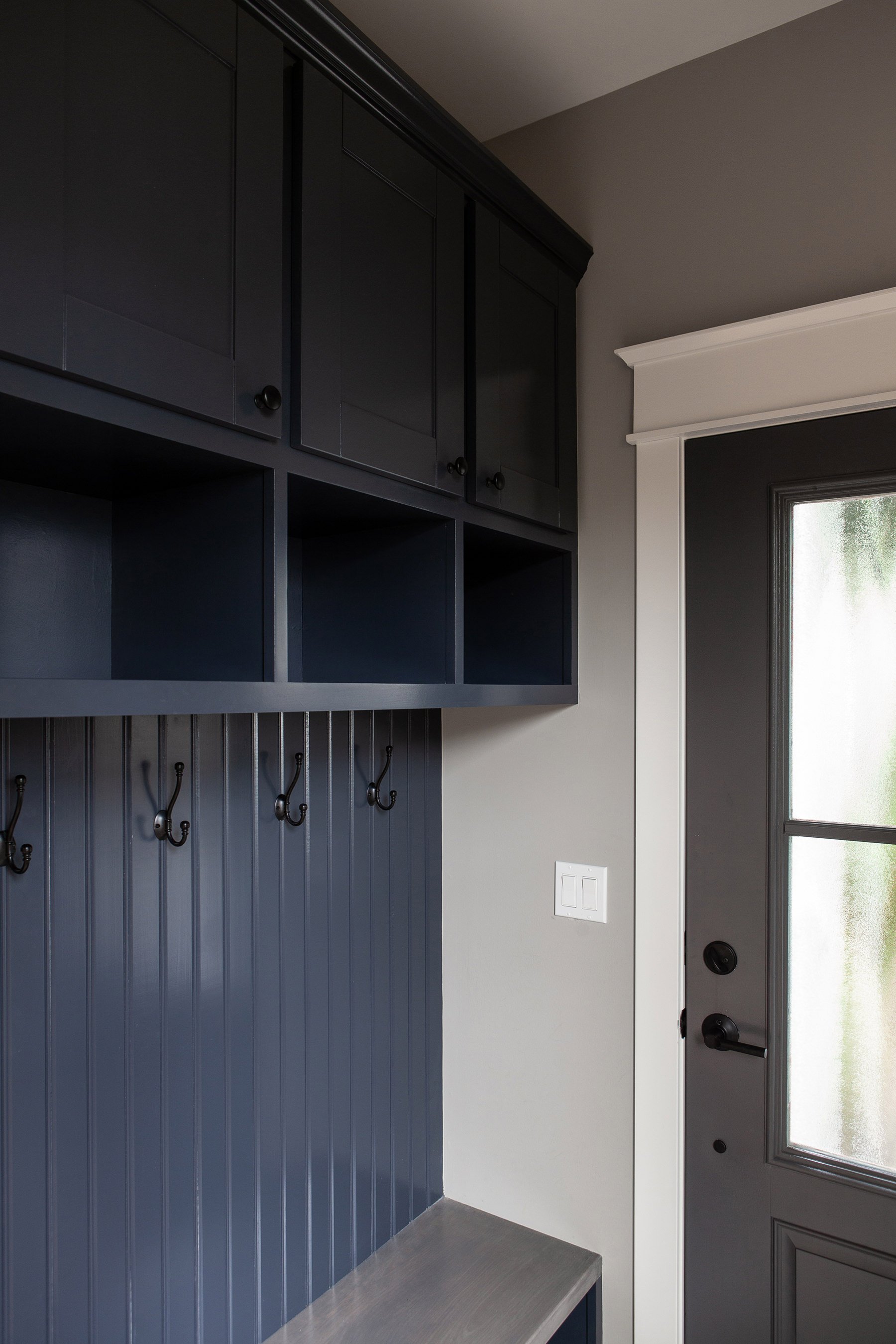 Navy mudroom trim with a beautiful classic black door.