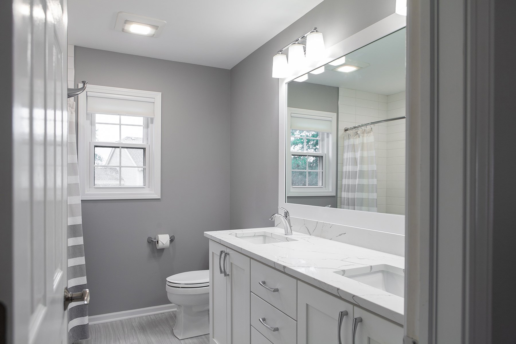 remodeled home bathroom with white cabinetry, light gray countertops and chrome finishes