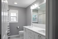 remodeled home bathroom with white cabinetry, light gray countertops and chrome finishes