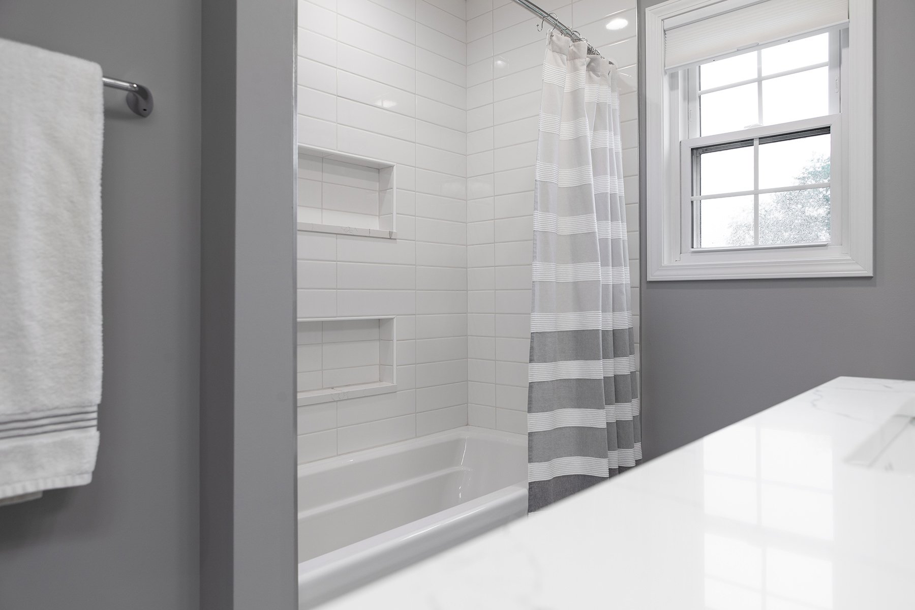 remodeled home bathroom with white cabinetry, light gray countertops and chrome finishes