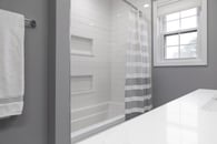 remodeled home bathroom with white cabinetry, light gray countertops and chrome finishes