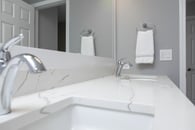 remodeled home bathroom with white cabinetry, light gray countertops and chrome finishes