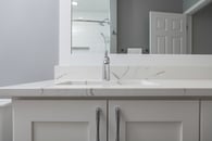 remodeled home bathroom with white cabinetry, light gray countertops and chrome finishes