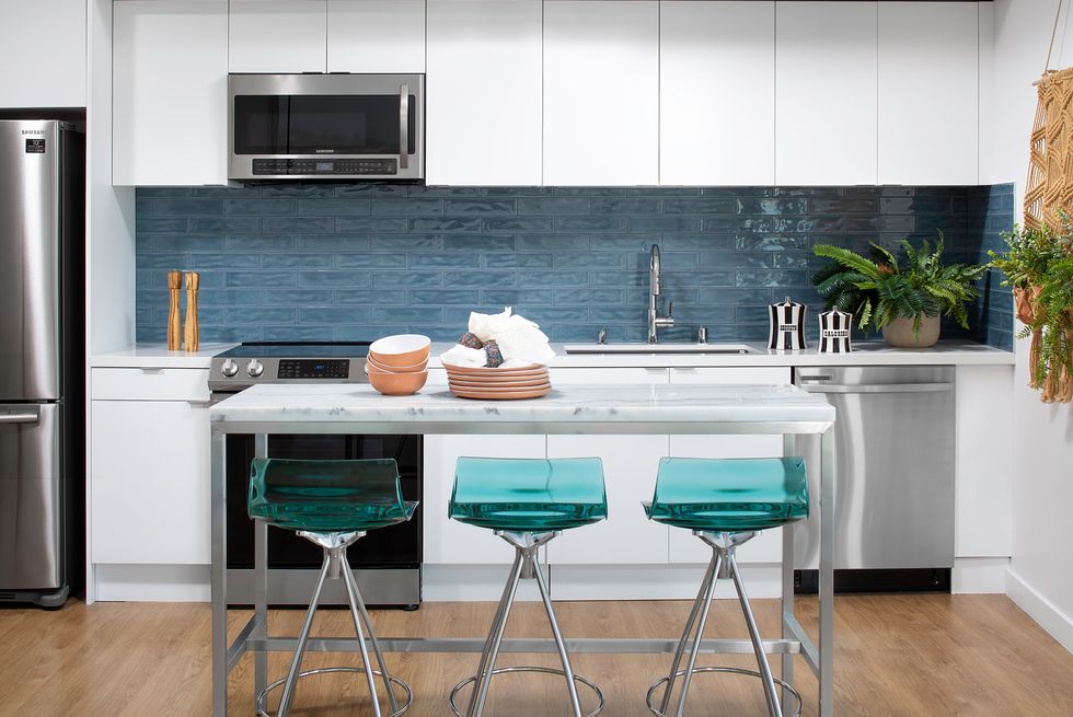 Open kitchen to living room with blue backsplash tiles and white kitchen cabinets.
