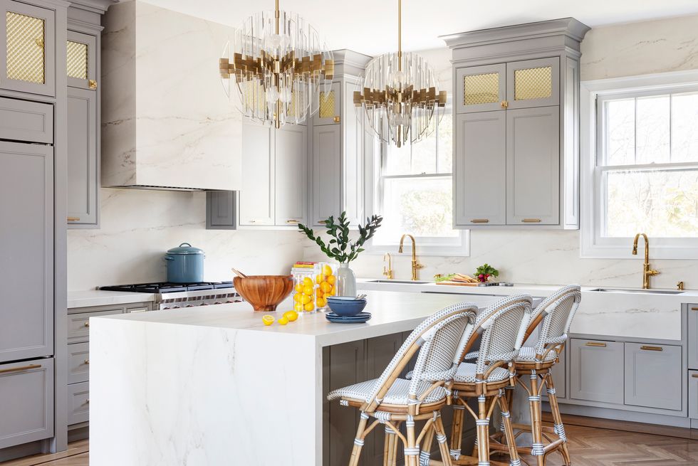 White waterfall marble kitchen island with marble backsplash and marble hood vent.