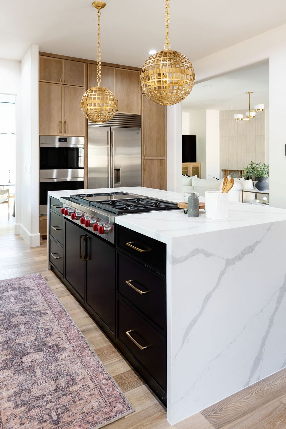 Bold kitchen colors with white marble countertop, black cabinets and wooden cabinet combination.