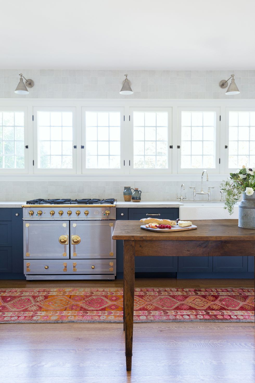 Vintage wooden dining table with an oriental rug, vintage stovetop in kitchen.