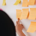 BDS team member pointing at a board of sticky notes with the work process outlined.