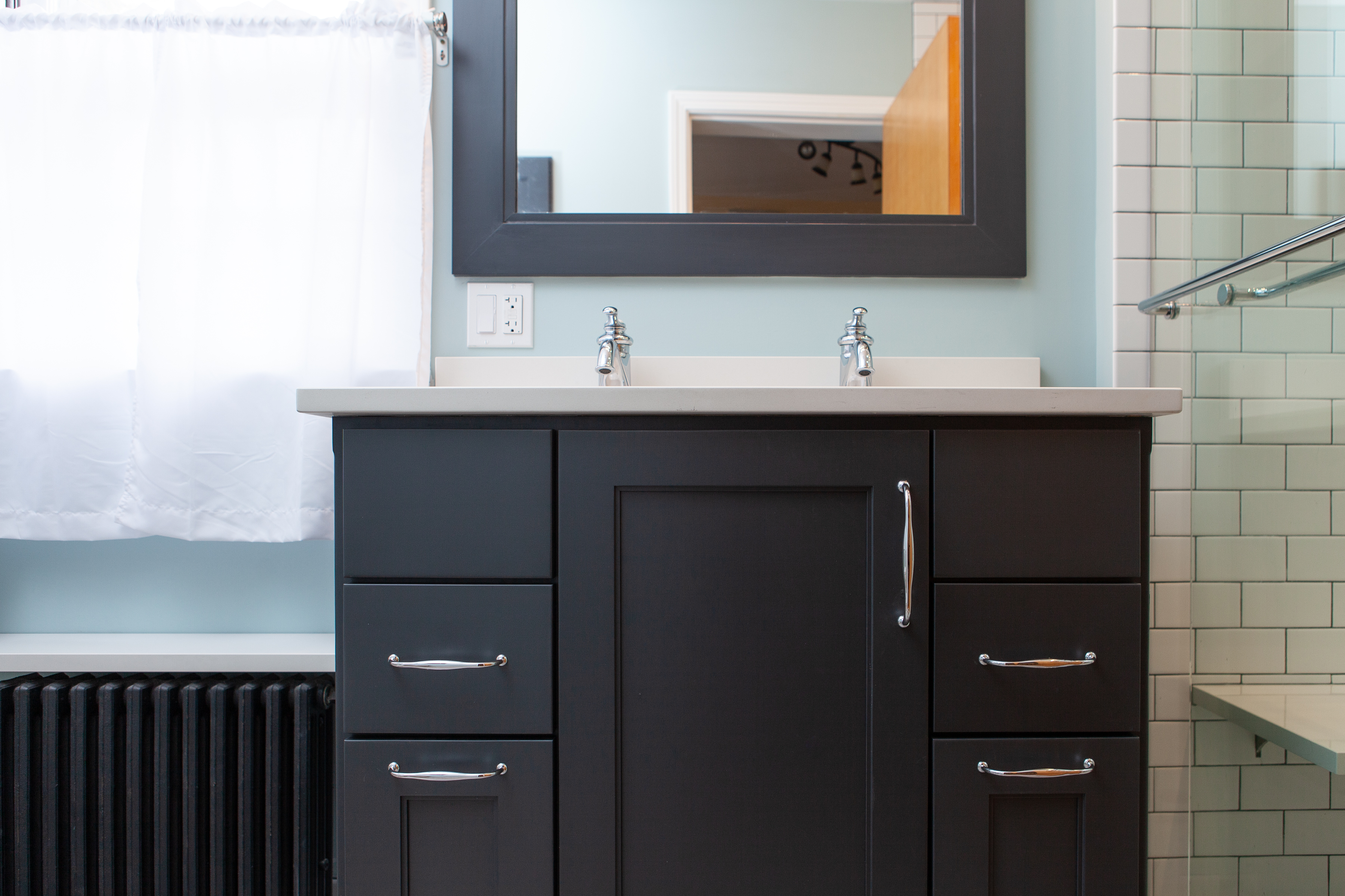 Chicago bathroom remodel with dark cabinets, double sink, dark mirror and painted floor heater.