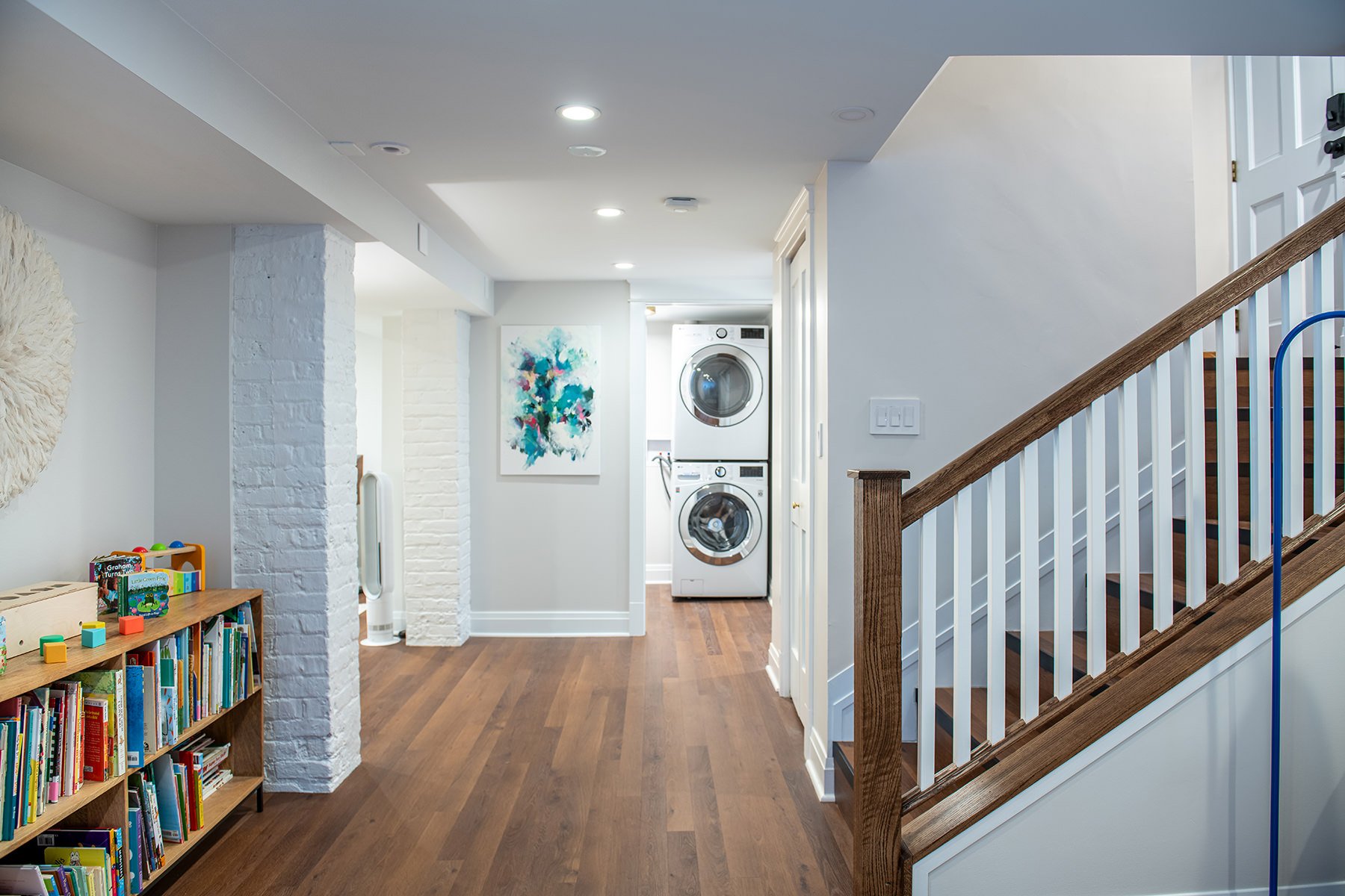 Basement with a wooden stairwell, vinyl flooring and light gray walls.