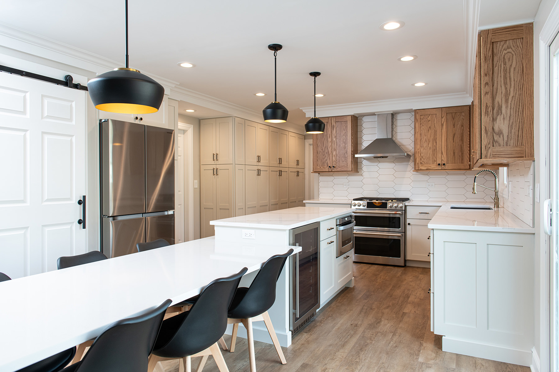 Modern farmhouse update in Libertyville with white countertops, white lower cabinets and wood upper cabinets. Modern black lights over the island and stainless steel appliances.
