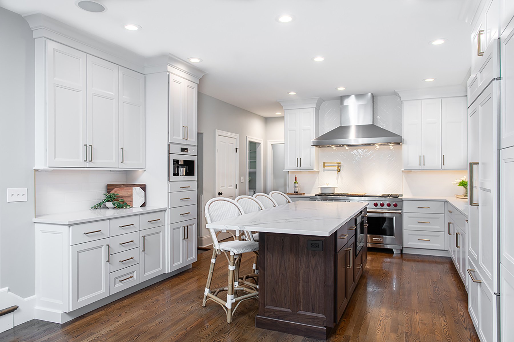 Traditional kitchen with modern finishes, white cabinets and wood flooring.