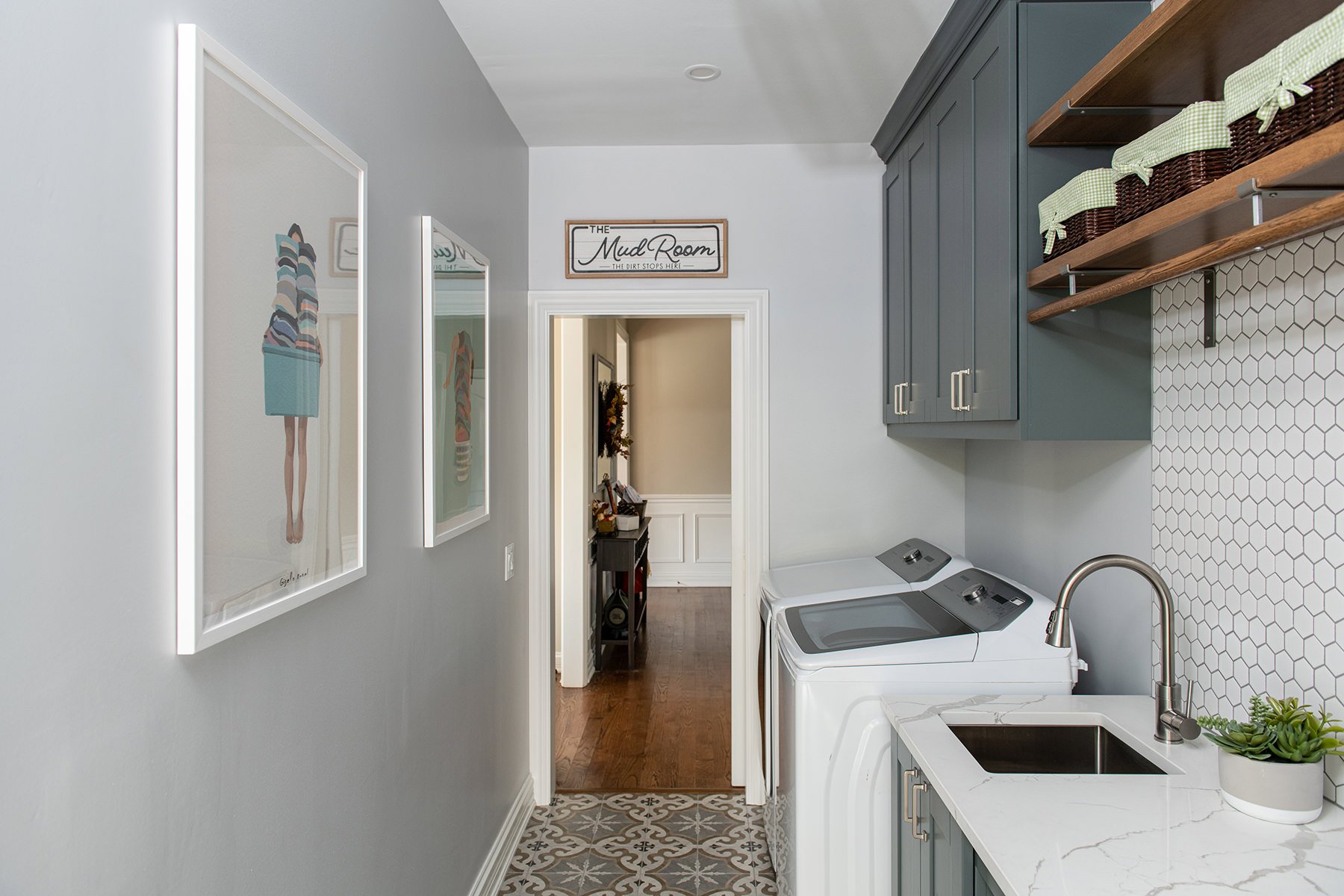 Remodeled mudroom with unique floor tiles, custom cabinetry and a washer and dryer next to a sink and counter top.