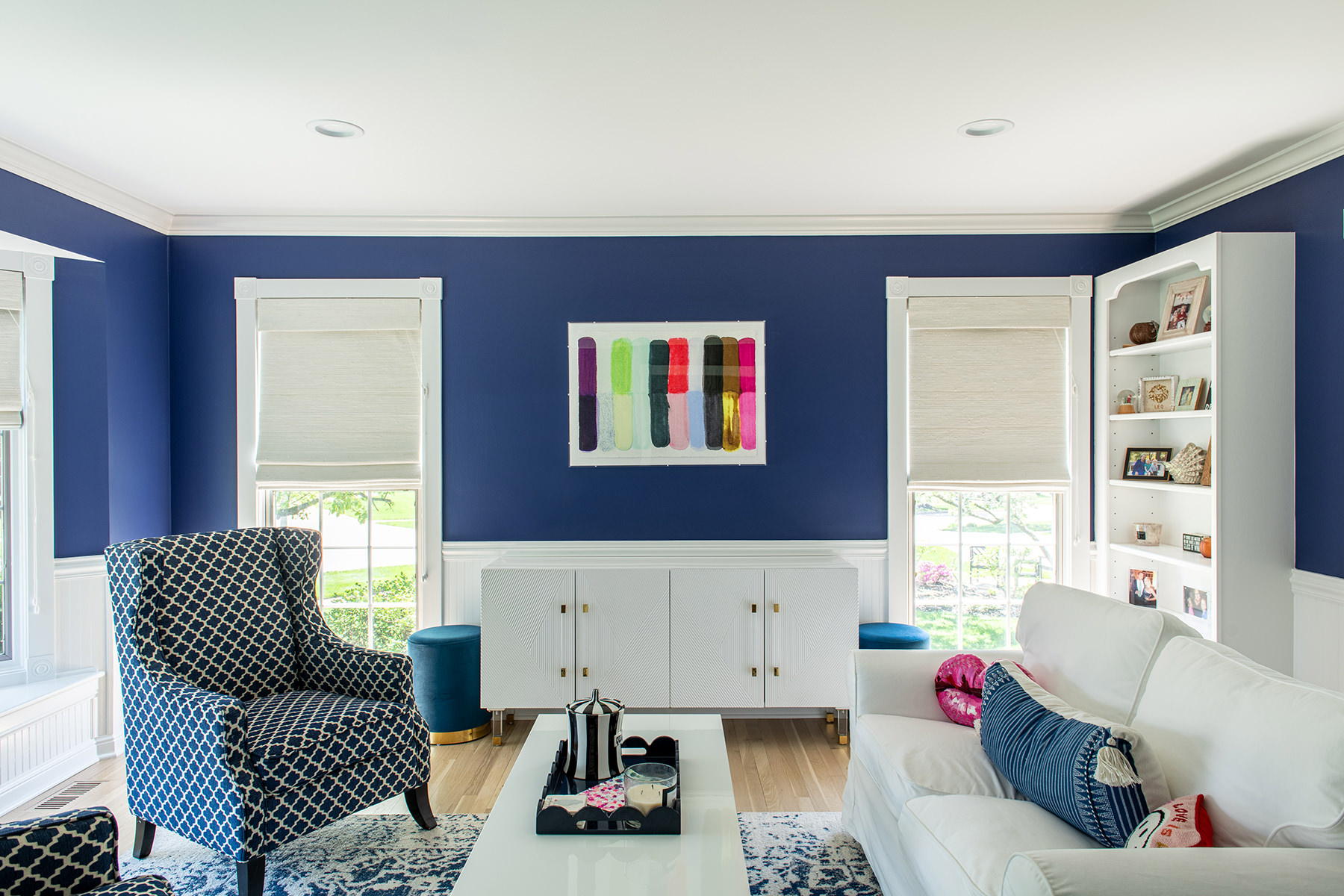 Living room with blue walls, white coffee table, gray chairs and a cream couch.