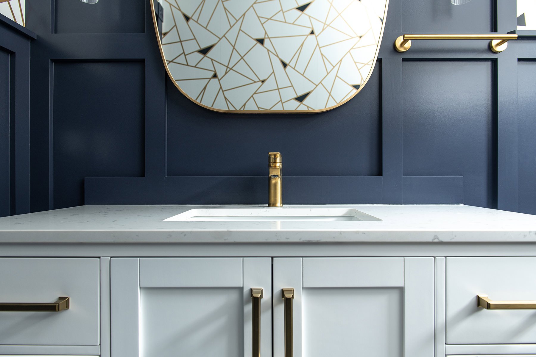 powder room with white cabinets, gold hardware and navy blue walls