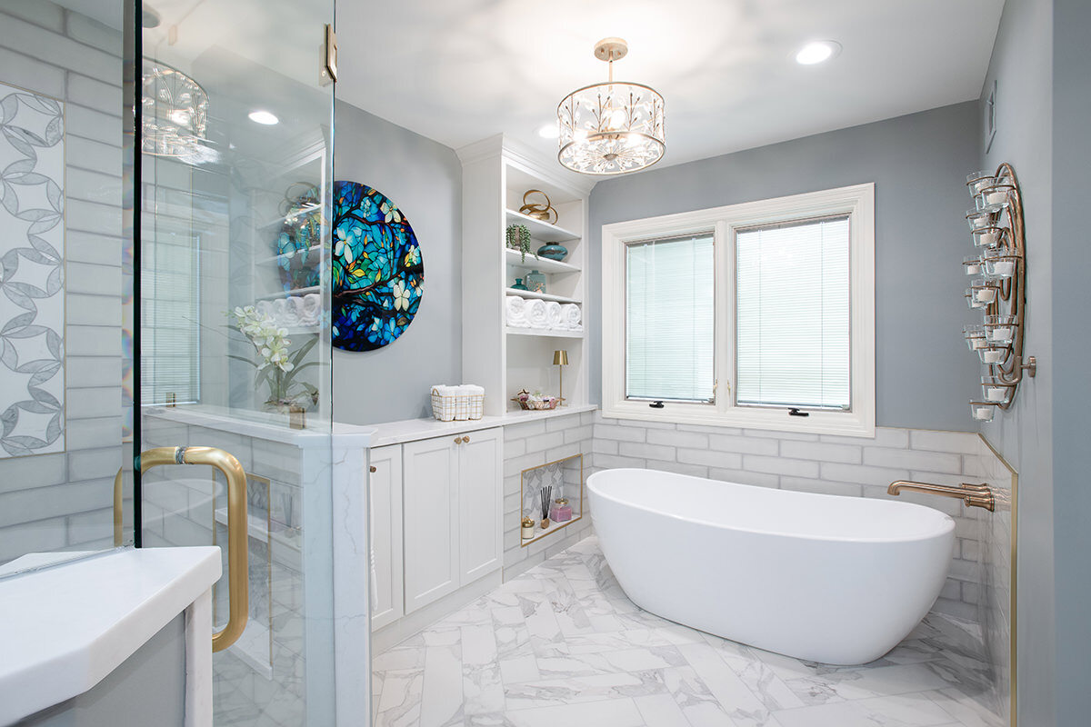 Updated primary bathroom with white cabinetry, white tile, a new freestanding tub, and enclosed glass shower.